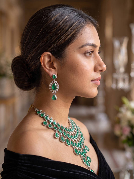 Woman wearing a green emerald necklace and earrings with a blurred background