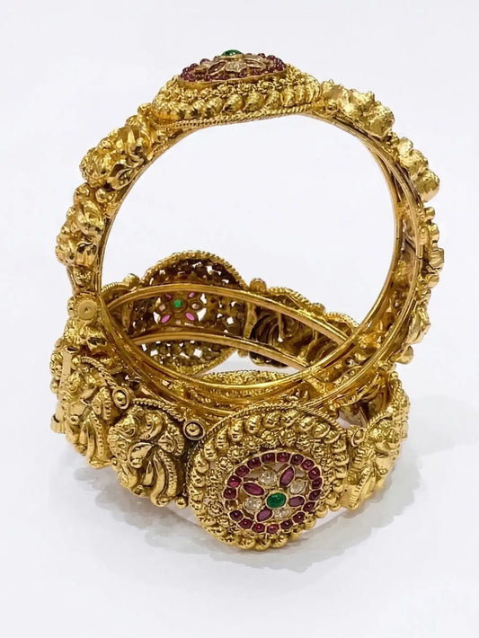Gold bracelet with intricate designs and gemstones on a white background