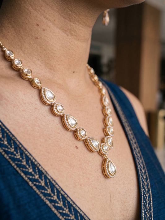 Gold necklace with pearls worn by a person in a blue outfit.