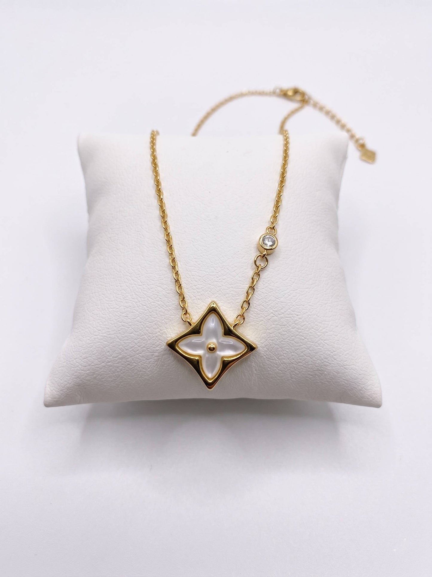 Gold necklace with a star-shaped pendant on a white cushion