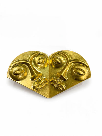 Gold decorative corner piece with face designs on a white background