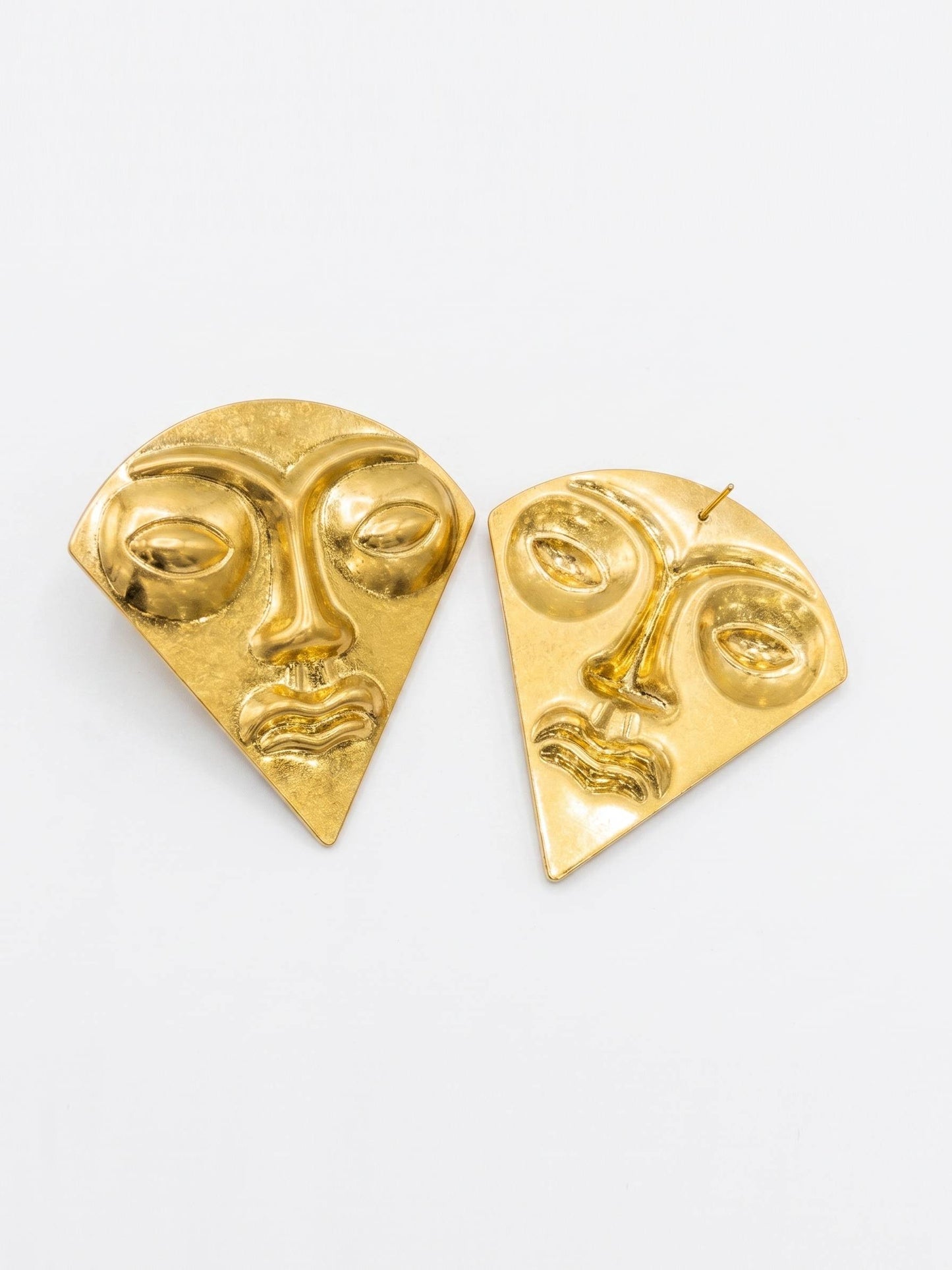 Gold face-shaped earrings on a white background