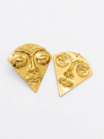 Gold face-shaped earrings on a white background