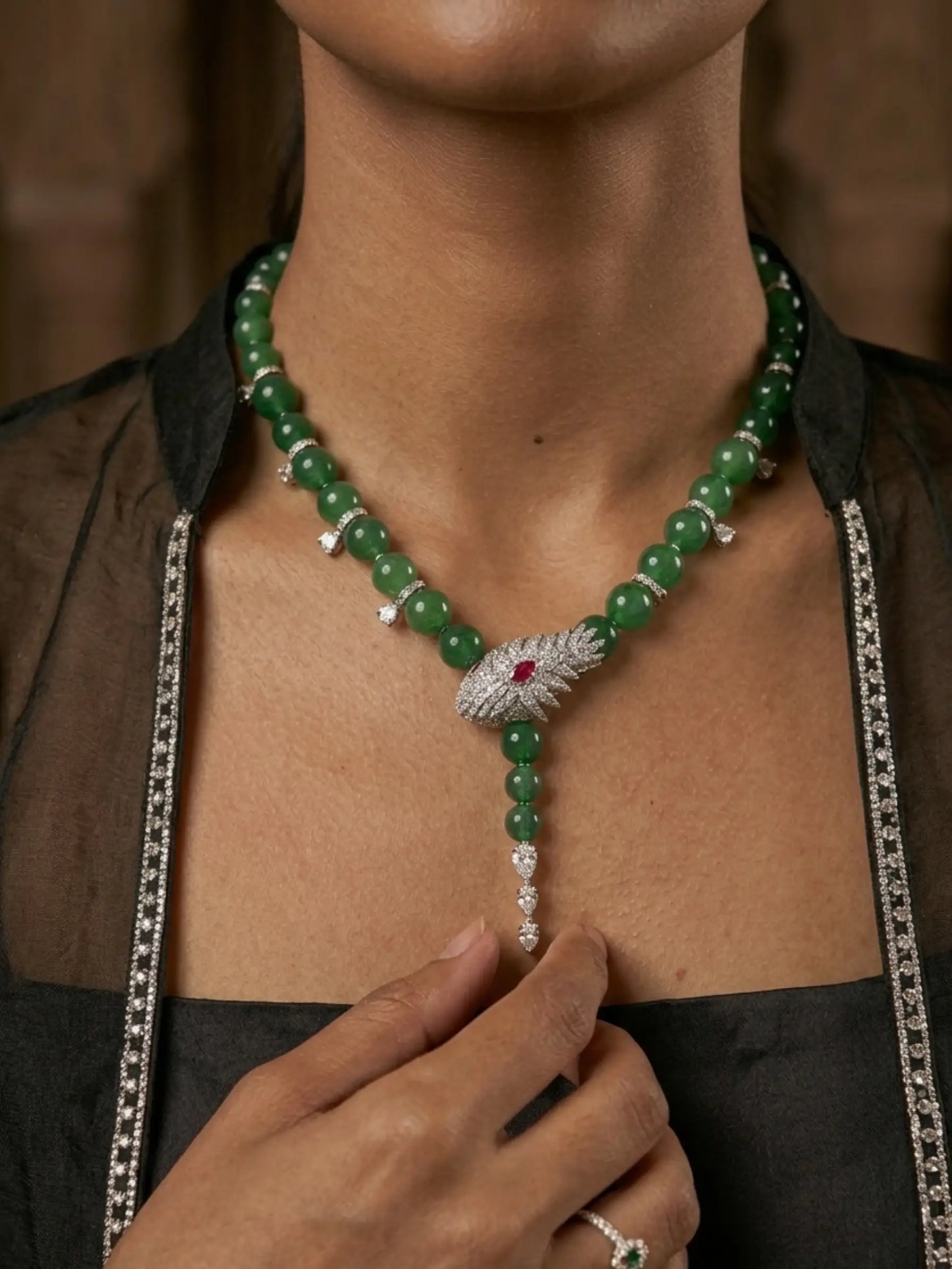 Green beaded necklace with a silver and red gemstone clasp worn by a person.
