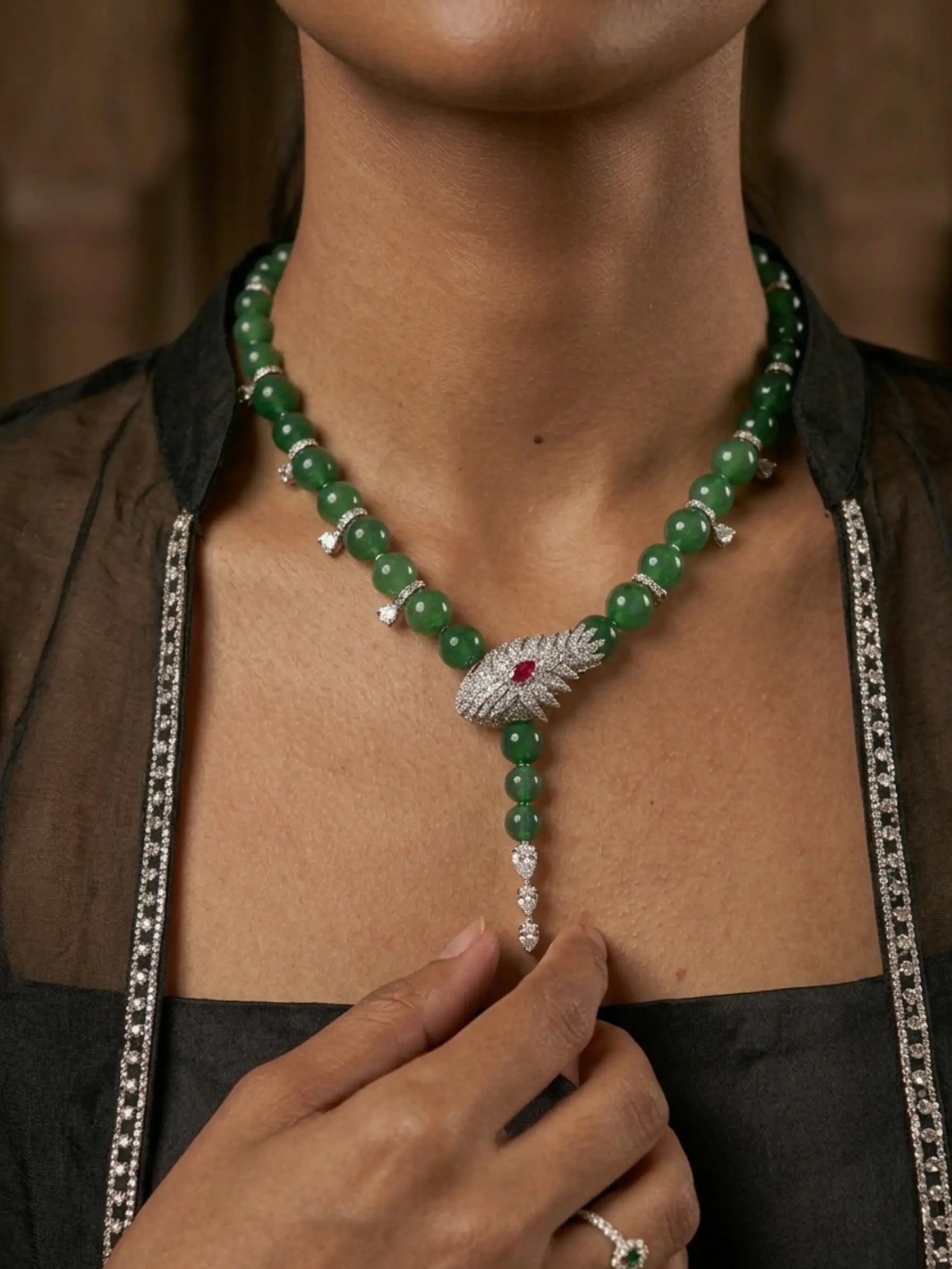 Green beaded necklace with a silver and red gemstone clasp worn by a person.