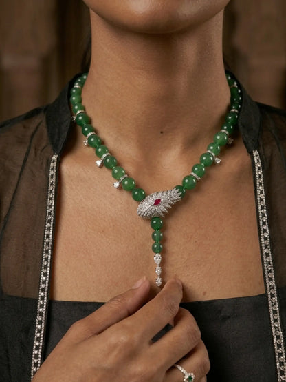 Green beaded necklace with a silver and red gemstone clasp worn by a person.