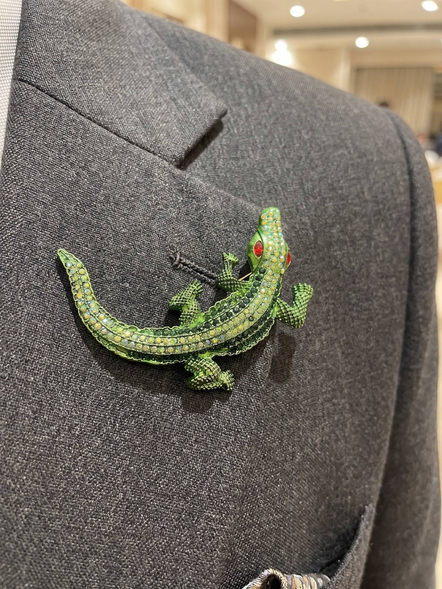 Green lizard brooch on a gray suit jacket