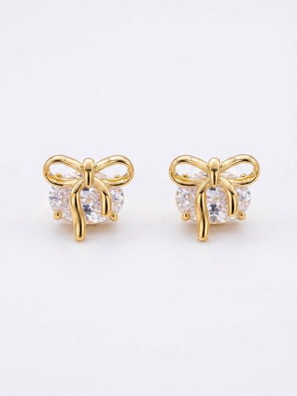 Gold bow-shaped earrings with clear gemstones on a white background