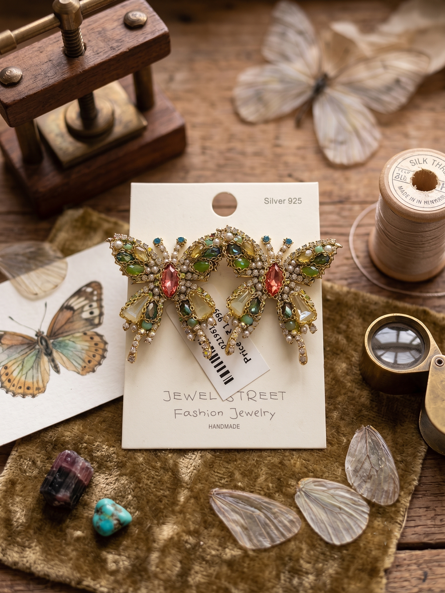 Decorative earrings on a 'Jewel Street' card with butterflies and vintage items in the background