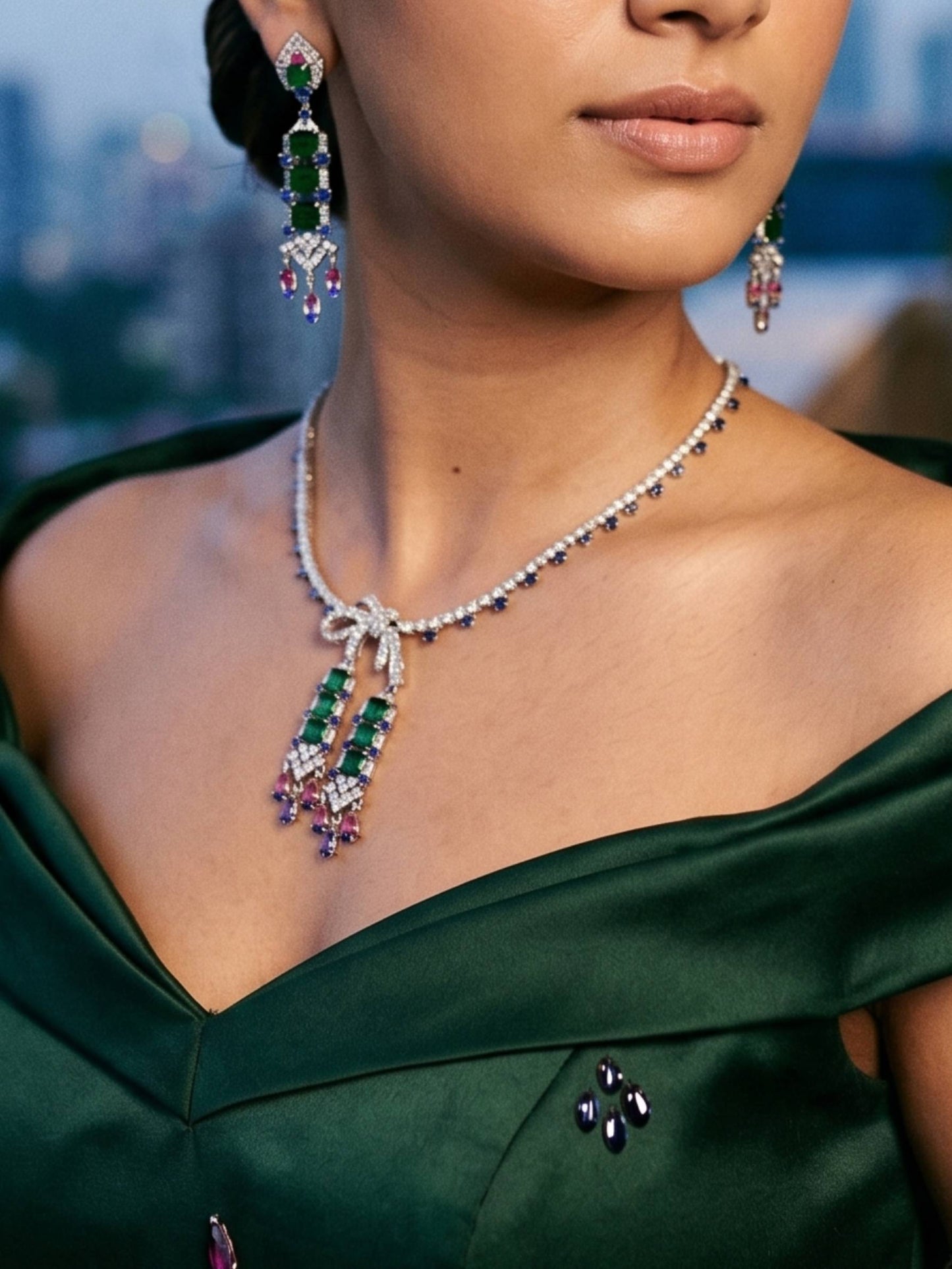 Close-up of a woman wearing a diamond necklace with emerald and purple gemstones, set against a blurred cityscape.