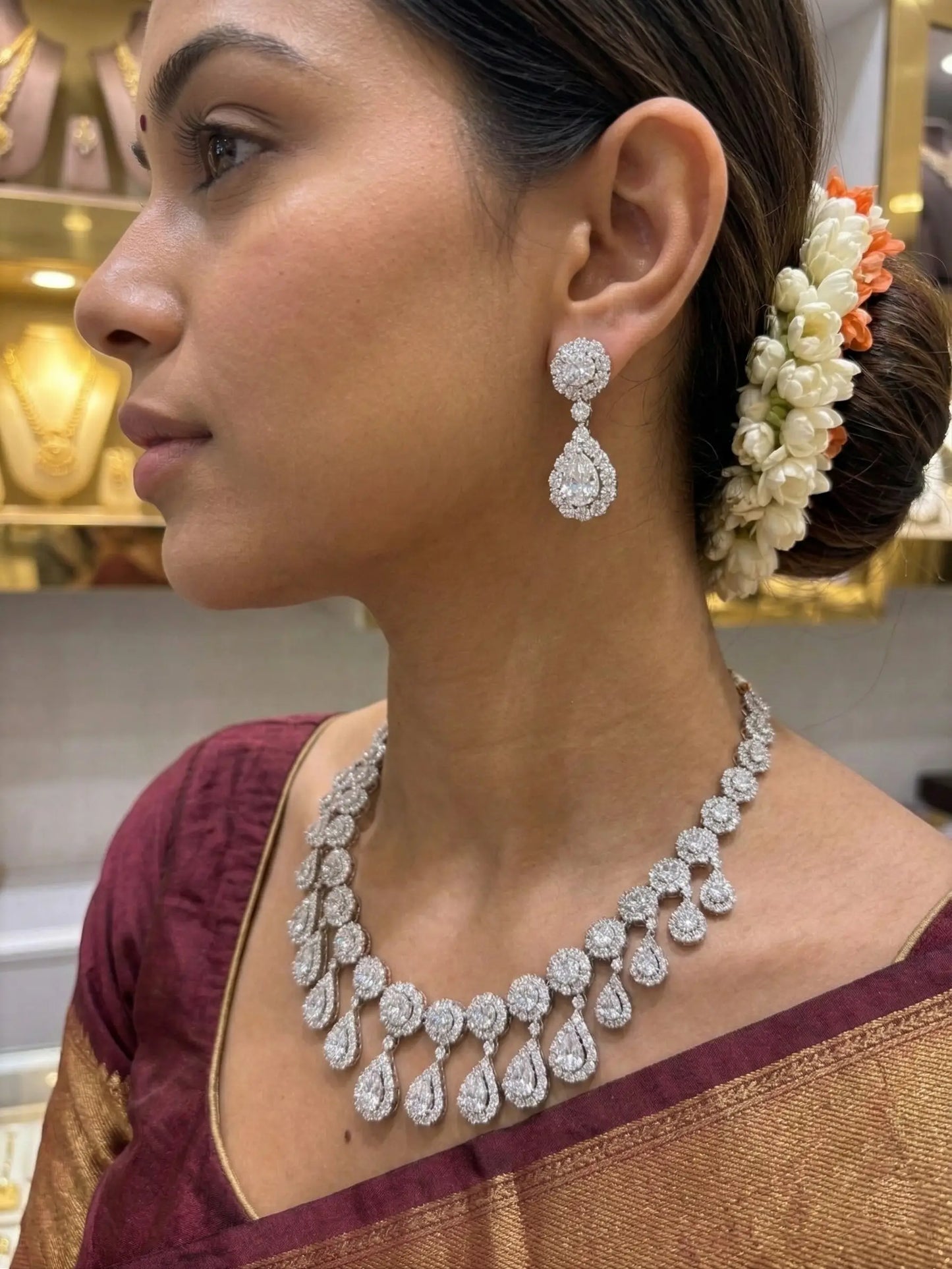 Woman wearing a diamond necklace and earrings with a blurred jewelry store background
