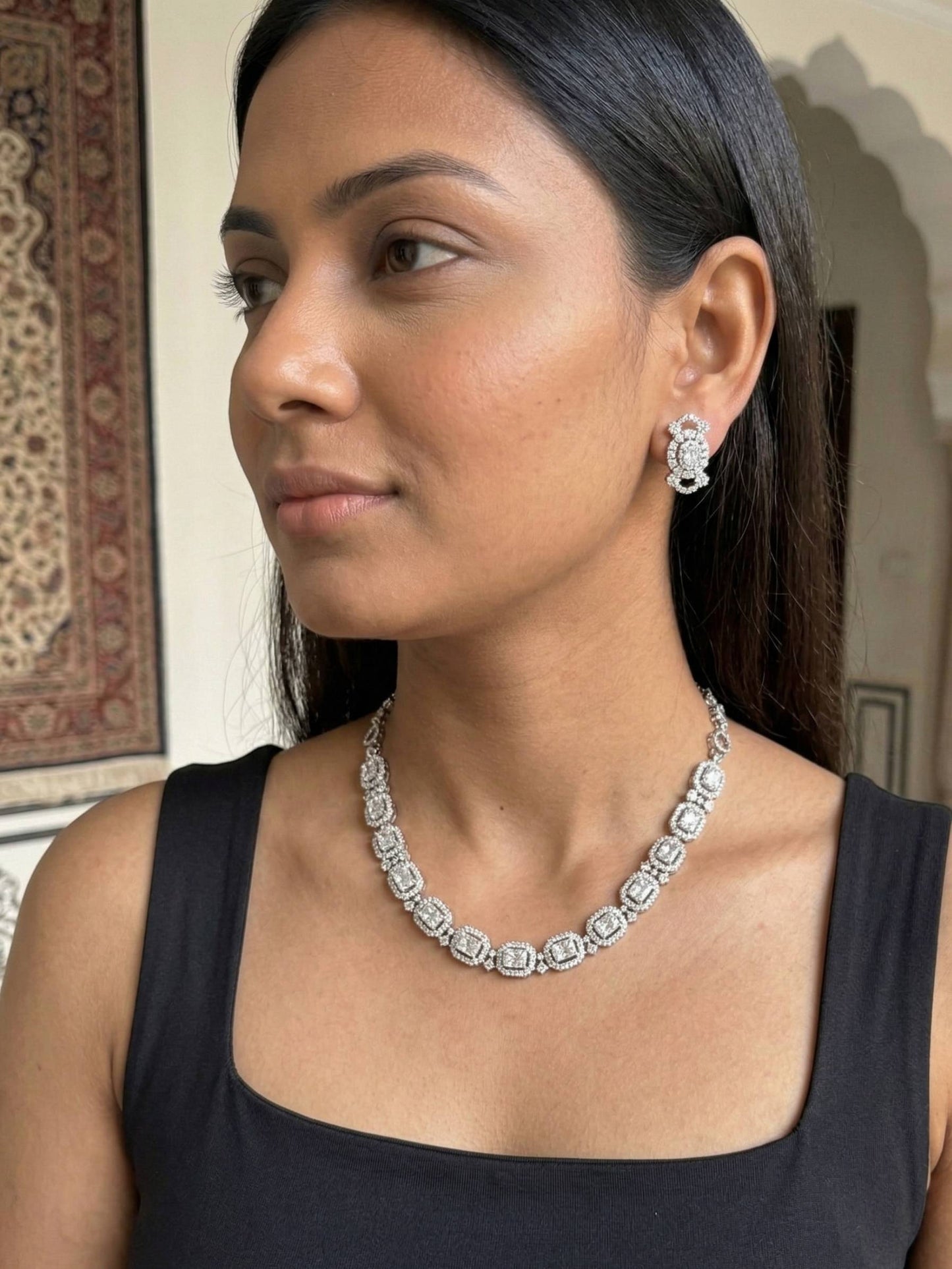Woman wearing a diamond necklace and earrings indoors