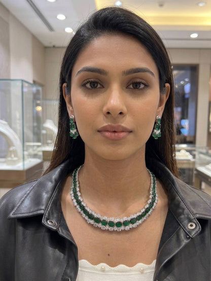 Woman wearing emerald and diamond jewelry in a jewelry store setting