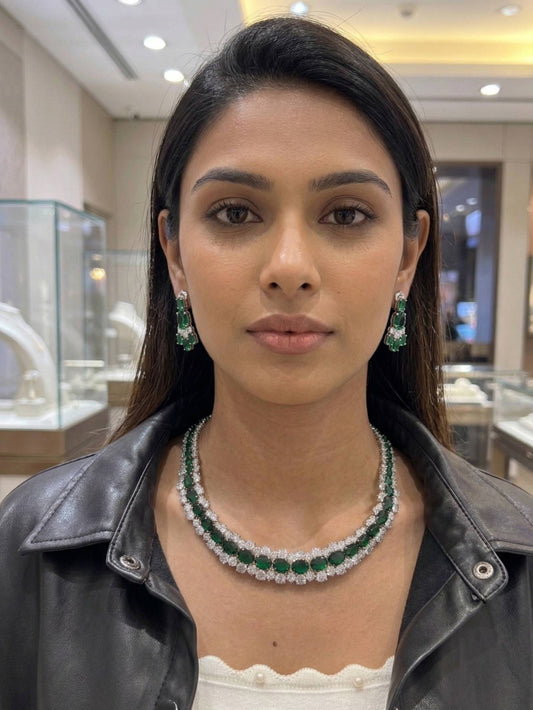 Woman wearing emerald and diamond jewelry in a jewelry store setting