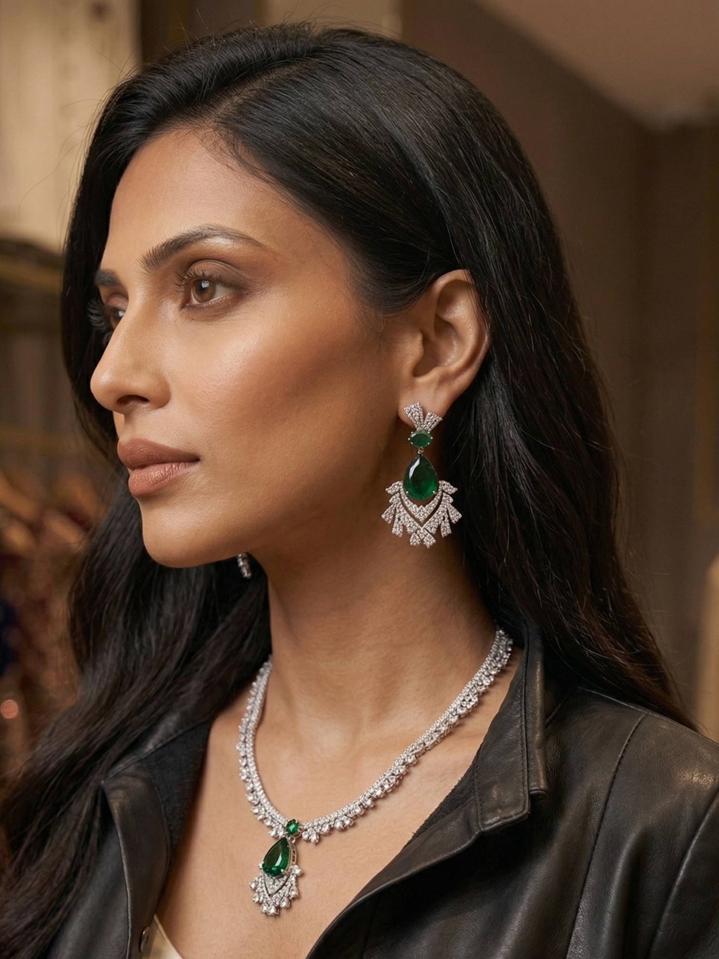 Woman wearing emerald and diamond jewelry with a blurred background