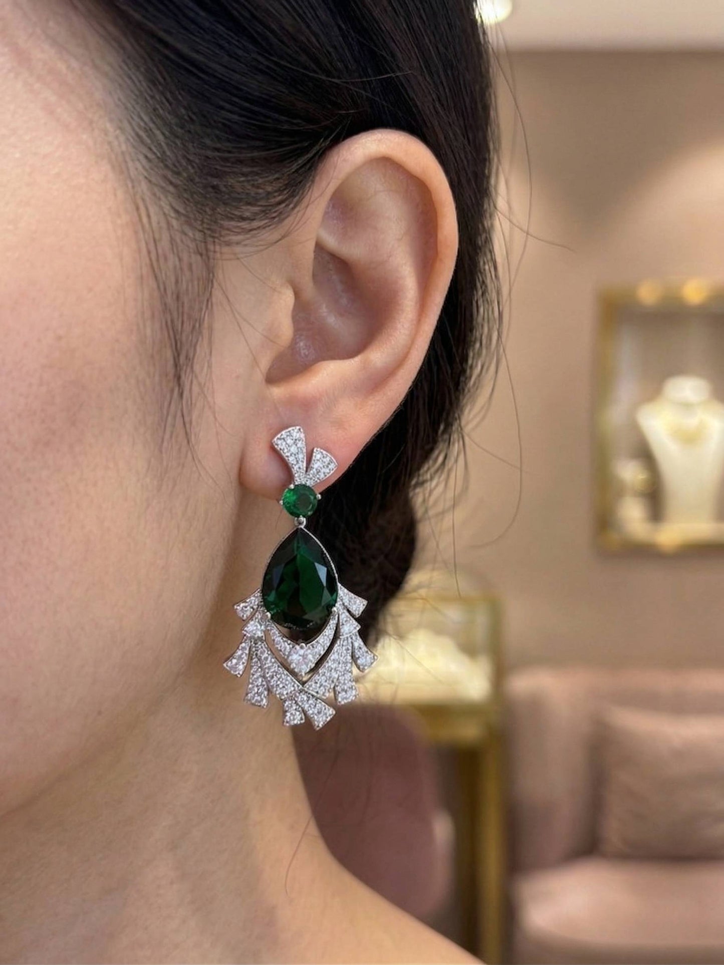 Close-up of a person wearing a green gemstone earring with a blurred background