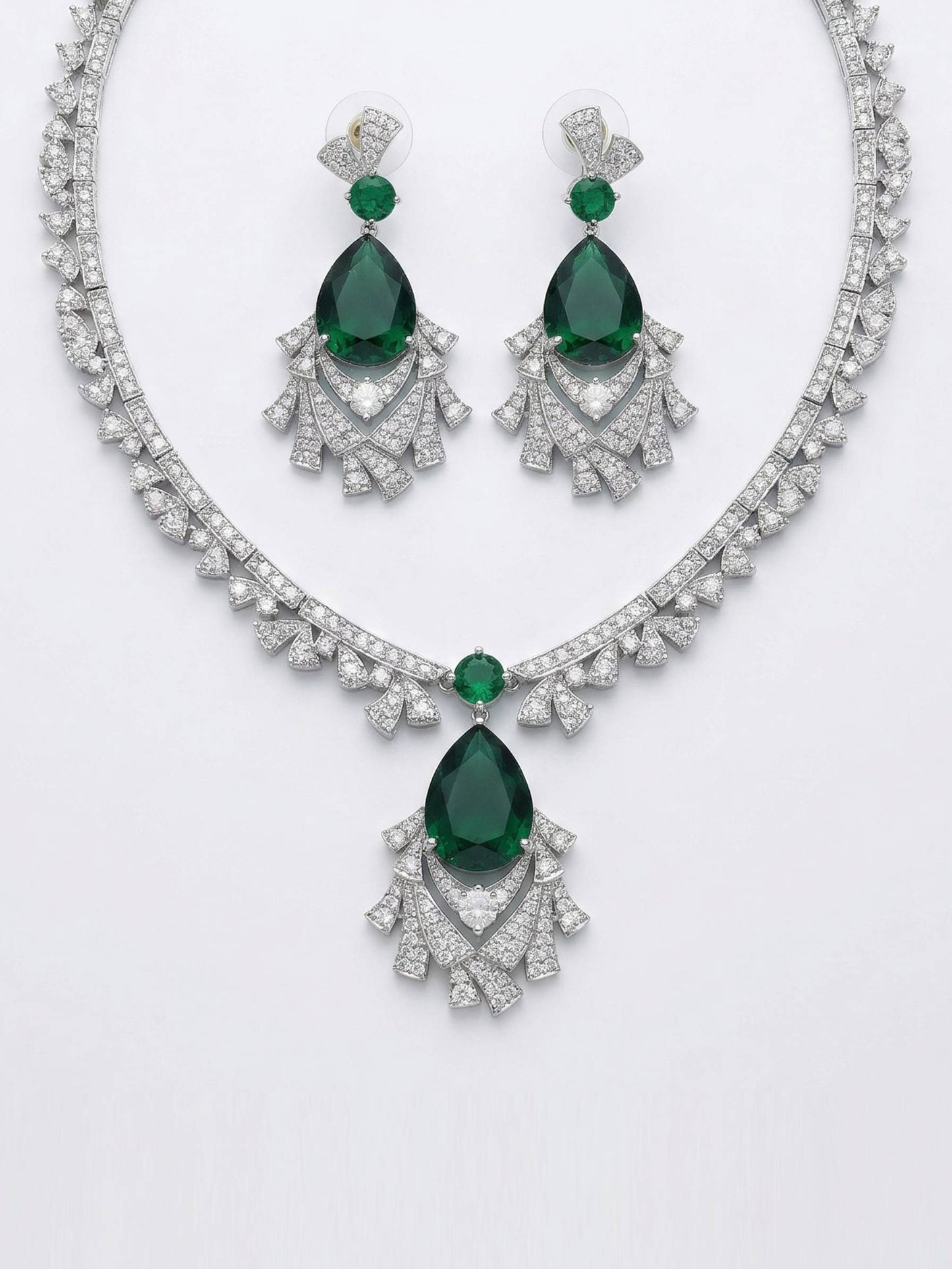 Jewelry set with emerald green gemstones and silver accents on a white background