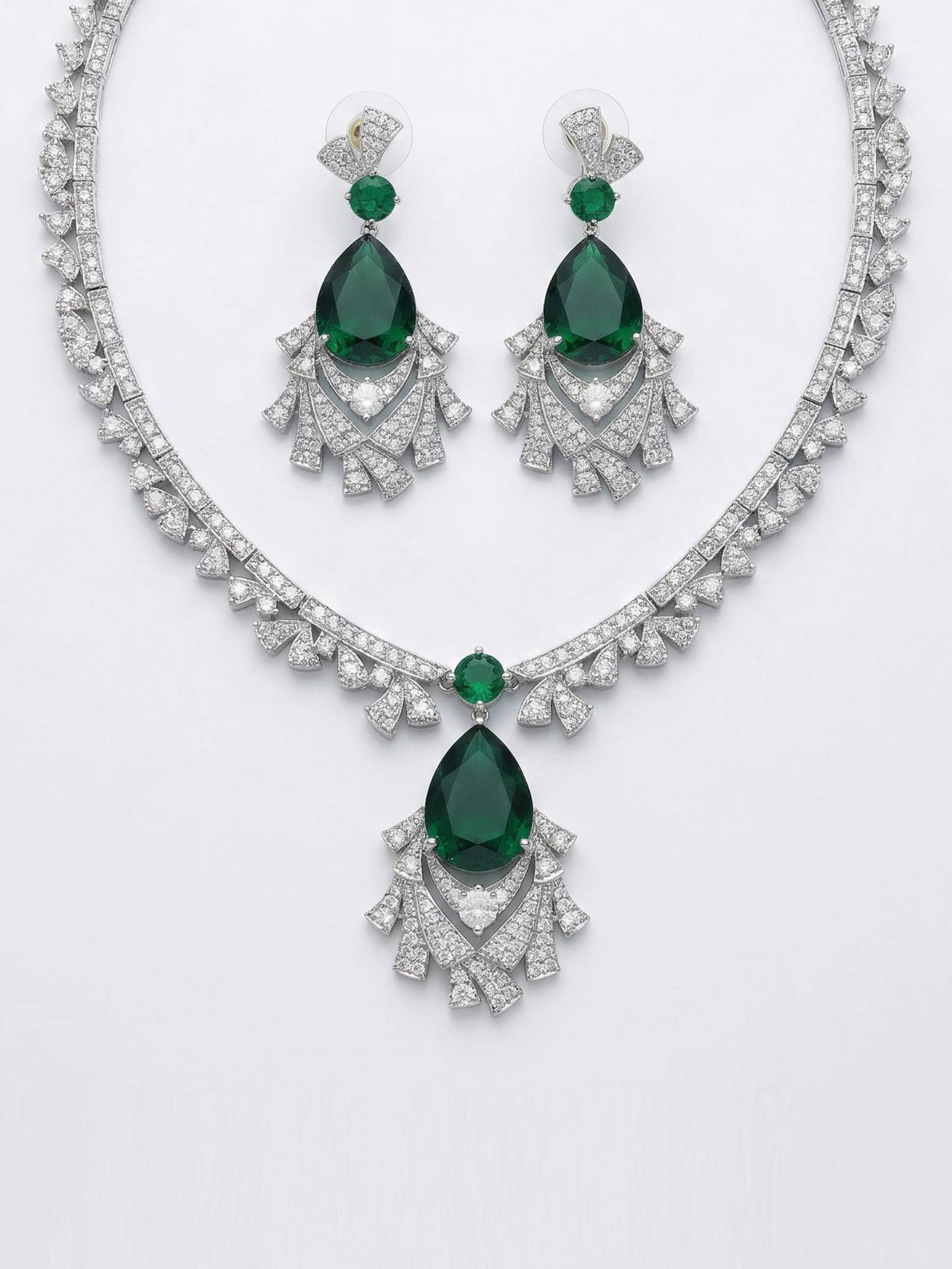 Jewelry set with emerald green gemstones and silver accents on a white background