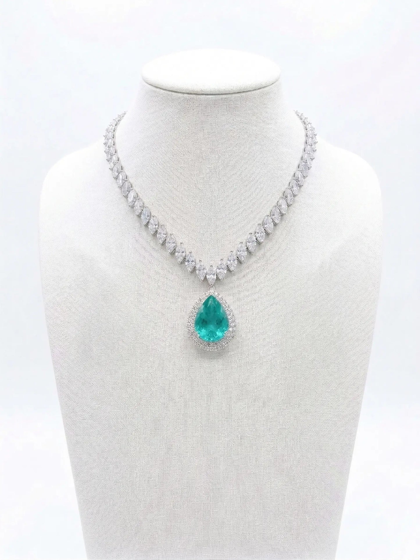 Necklace with a green teardrop pendant on a mannequin bust against a white background