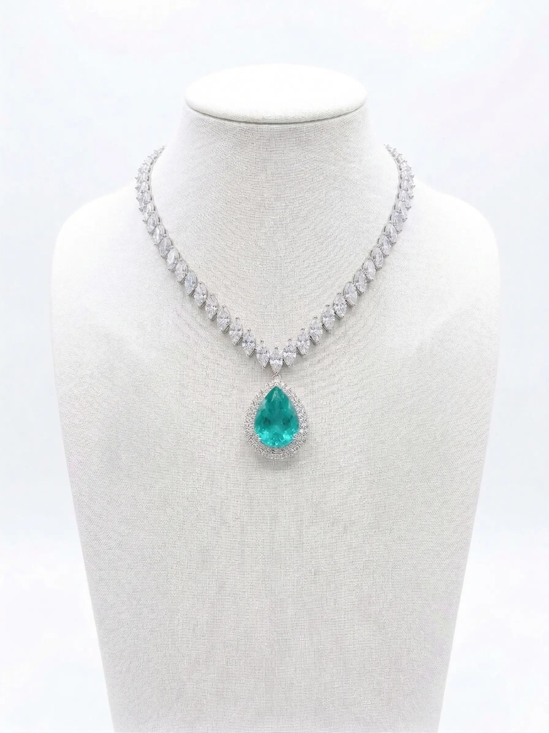 Necklace with a green teardrop pendant on a mannequin bust against a white background