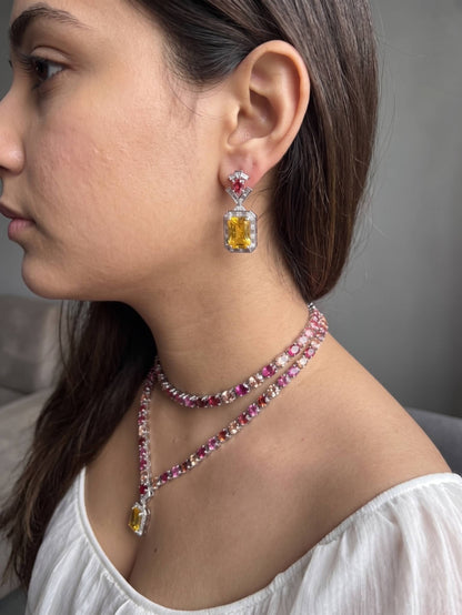 Close-up of a woman wearing a necklace and earrings with gemstones.