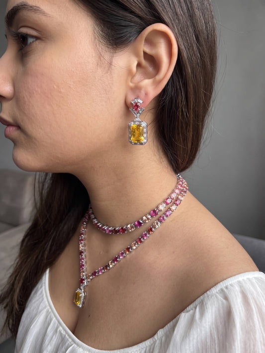 Close-up of a woman wearing a necklace and earrings with gemstones.
