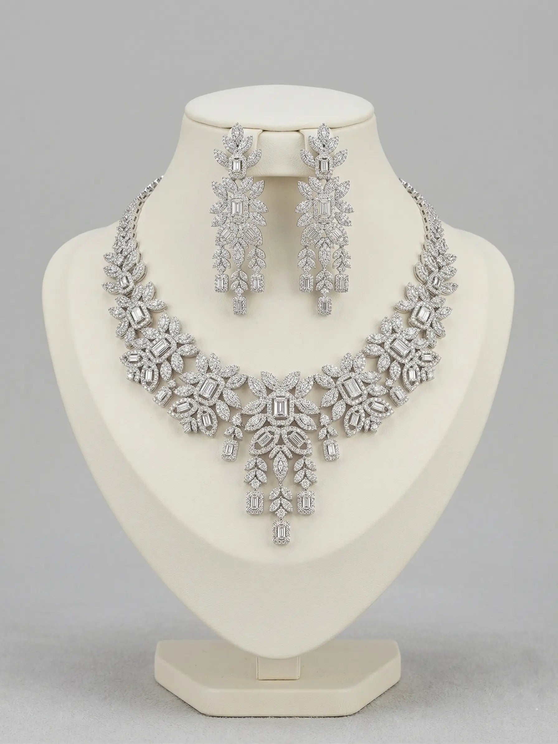 Silver necklace and earrings set on a mannequin bust against a gray background