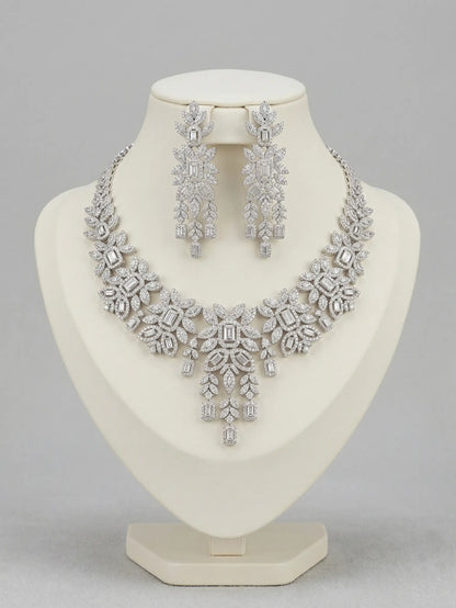 Silver necklace and earrings set on a mannequin bust against a gray background