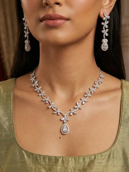 Woman wearing a diamond necklace and earrings with a green top.