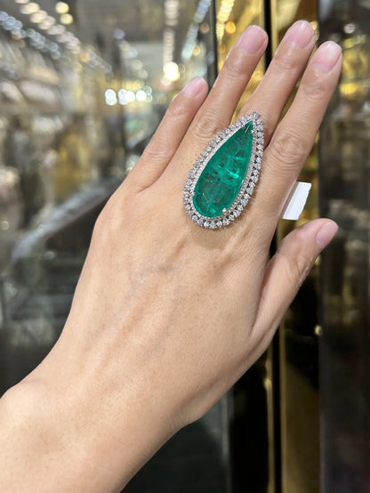 Hand wearing a large emerald ring with a blurred background