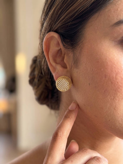 Close-up of a person wearing gold earrings with a blurred background