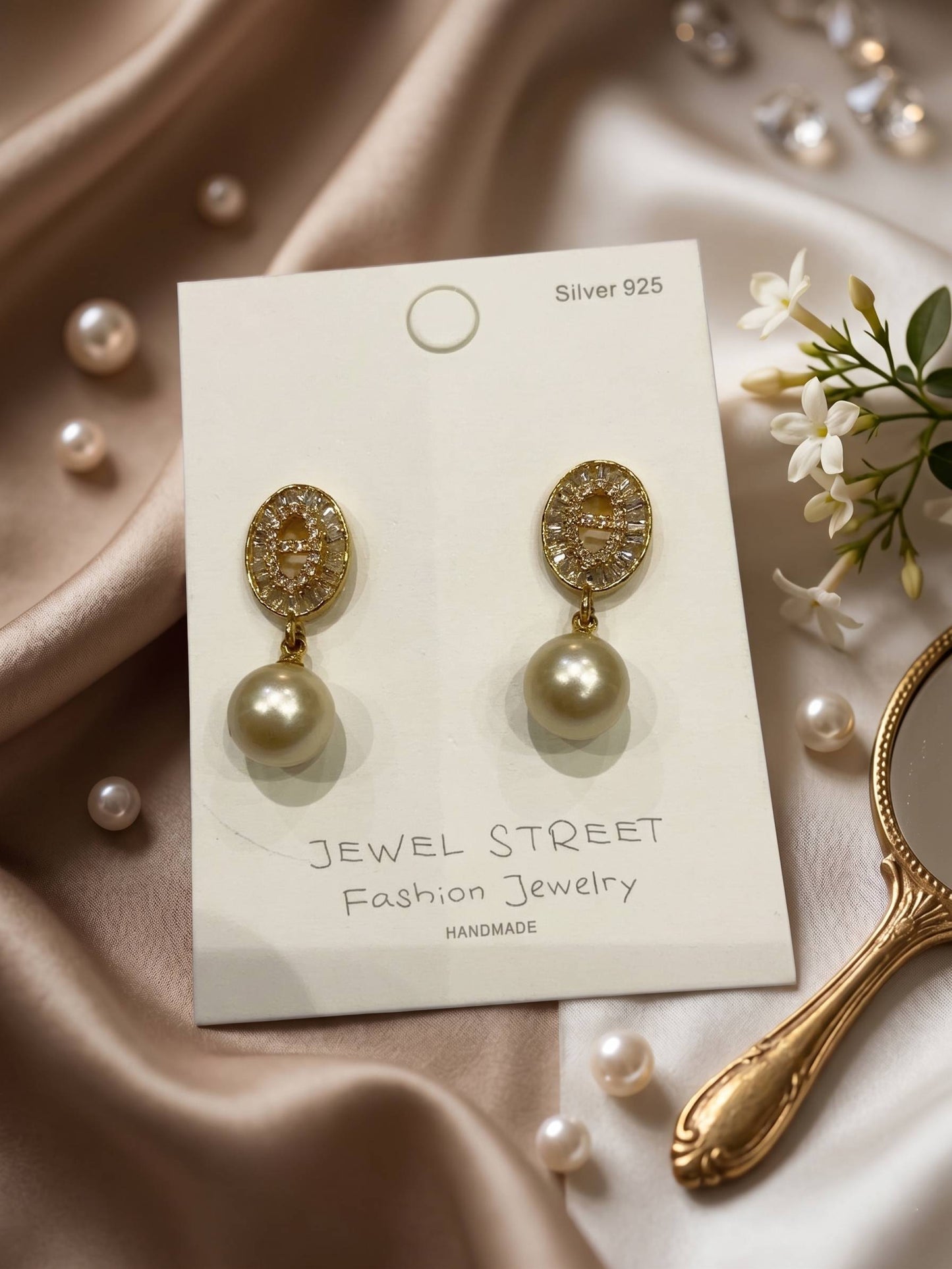Pearl earrings on a 'Jewel Street' card with a vintage mirror and pearls in the background.