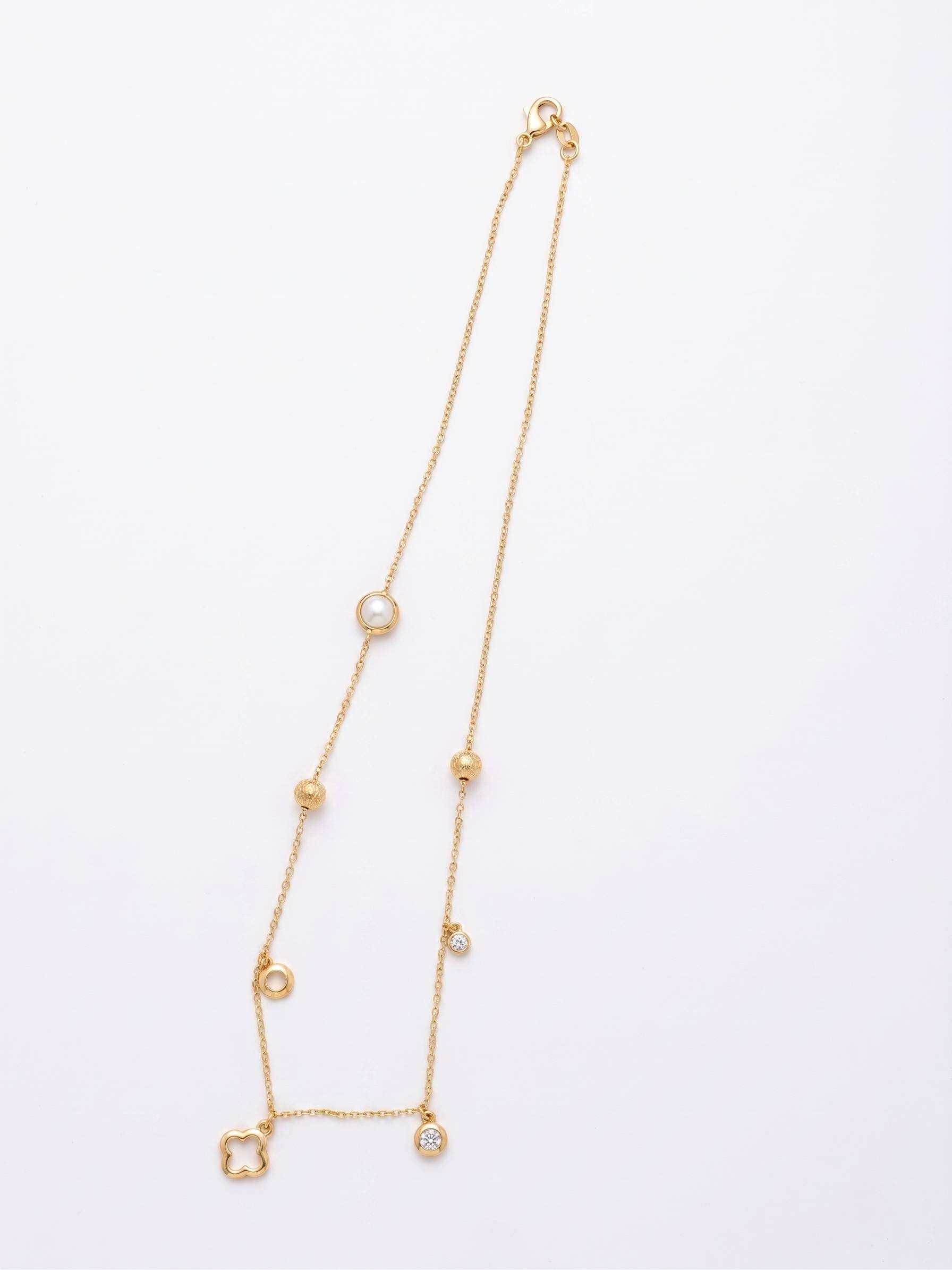 Gold necklace with small gemstones on a light gray background