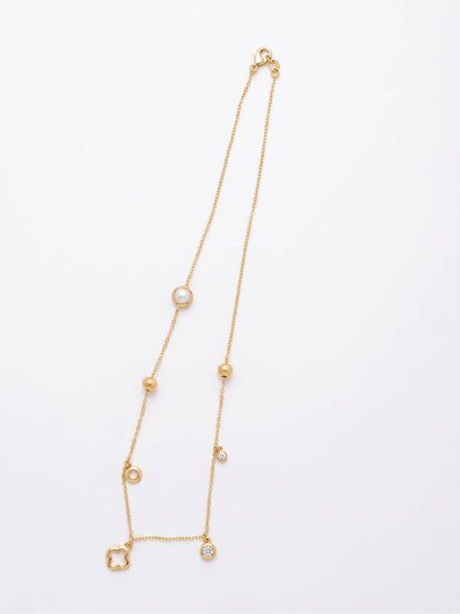 Gold necklace with small gemstones on a light gray background