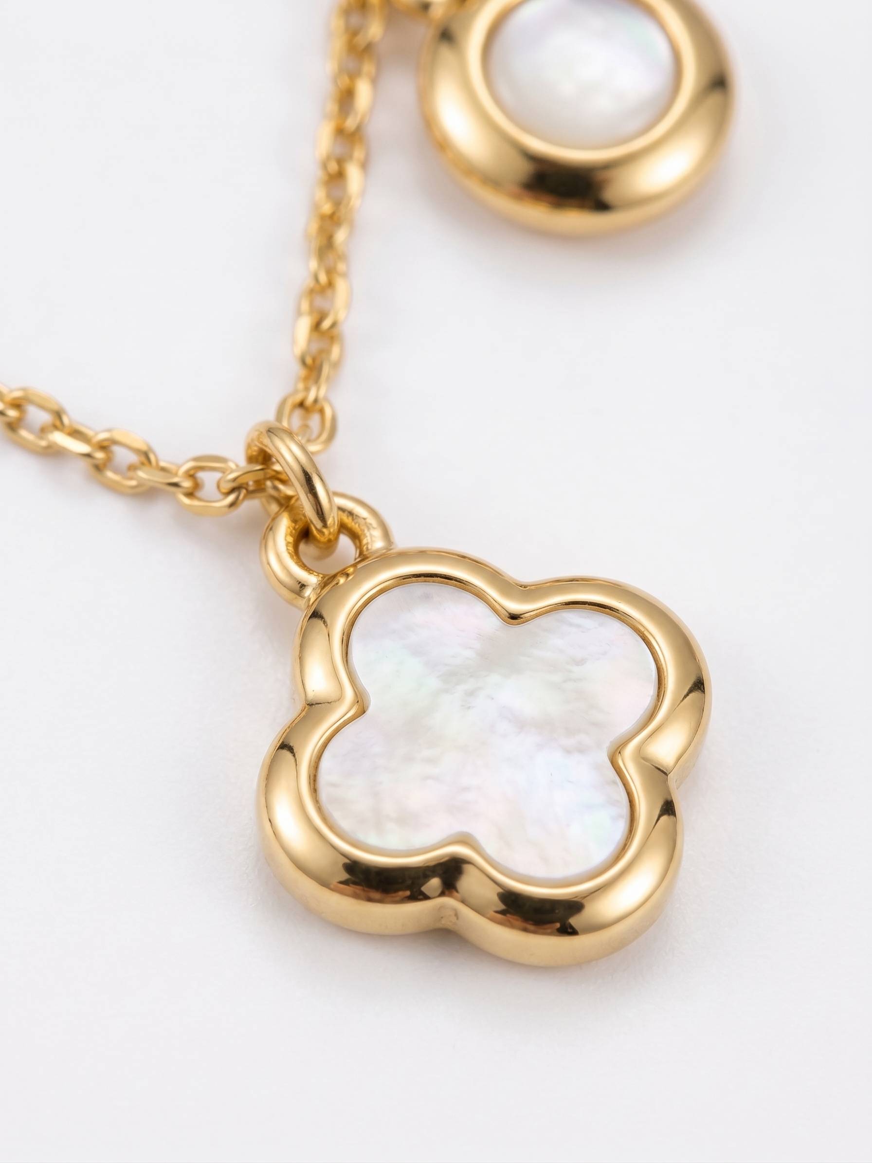 Gold necklace with a clover-shaped pendant on a white background