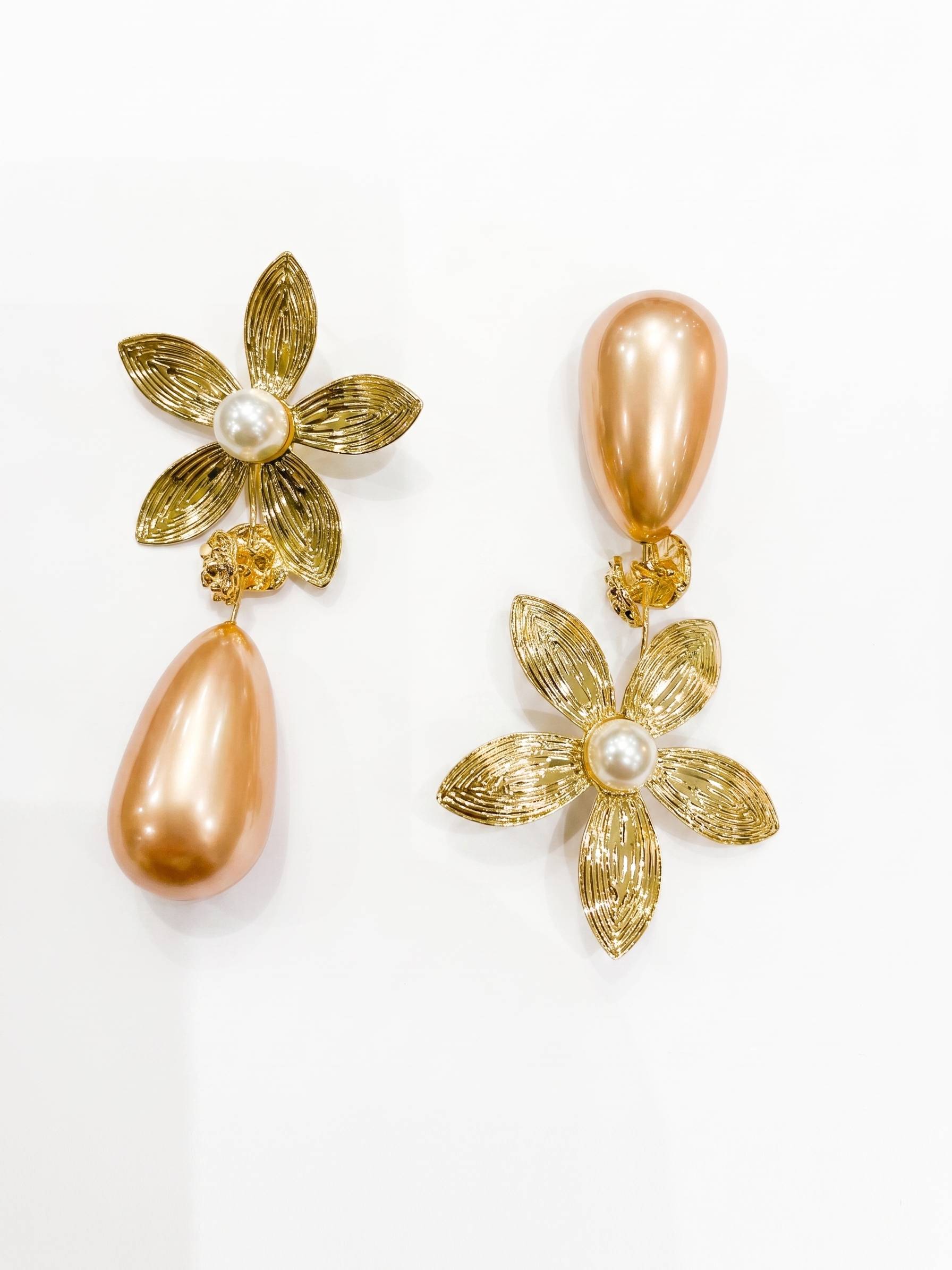 Gold floral earrings with pearls on a white background