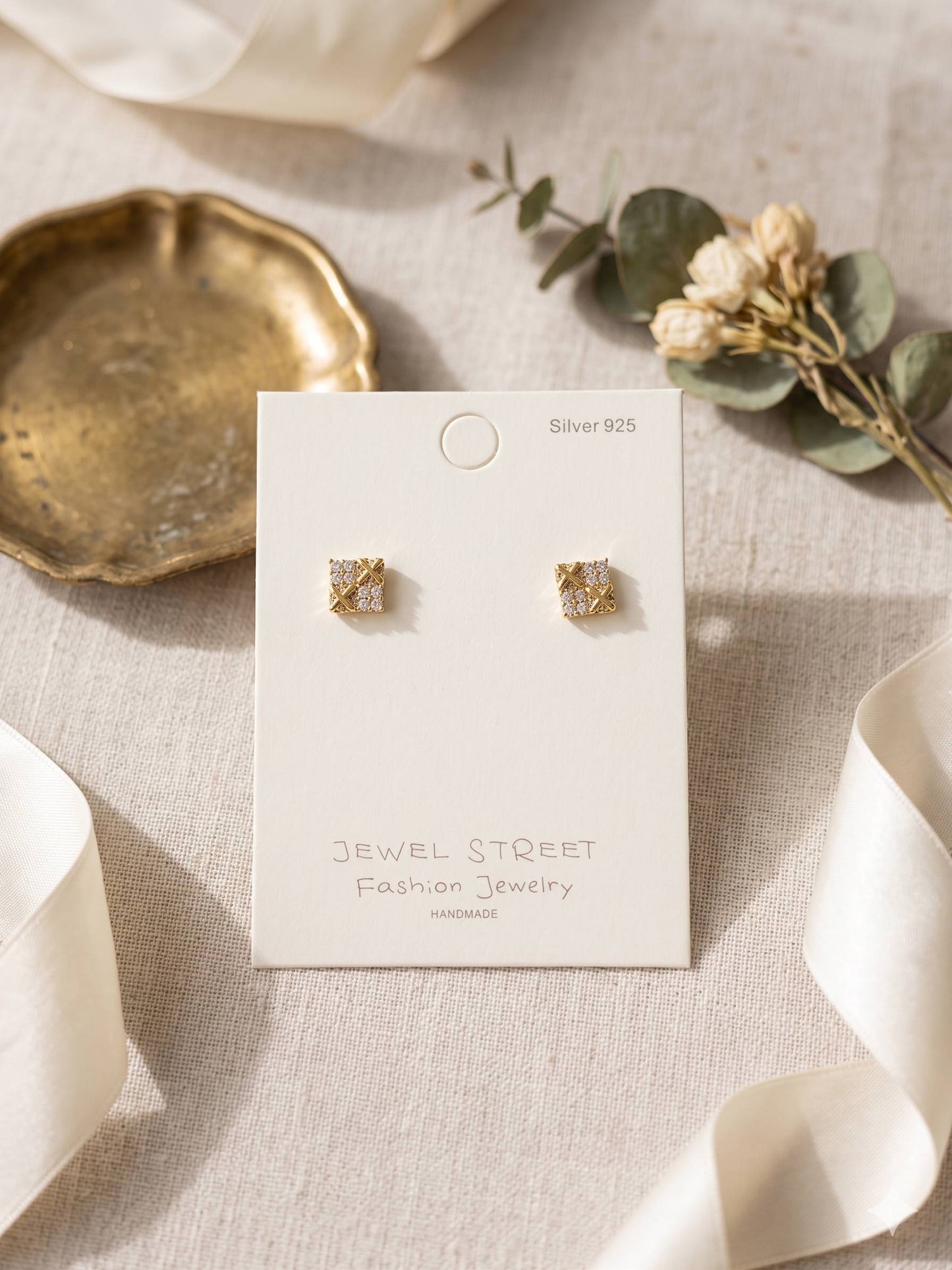 Gold earrings on a 'Jewel Street' branded card with a neutral background