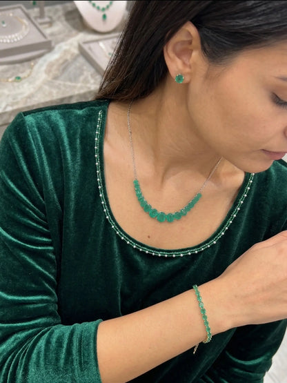 Woman wearing green jewelry including a necklace, earrings, and bracelet.