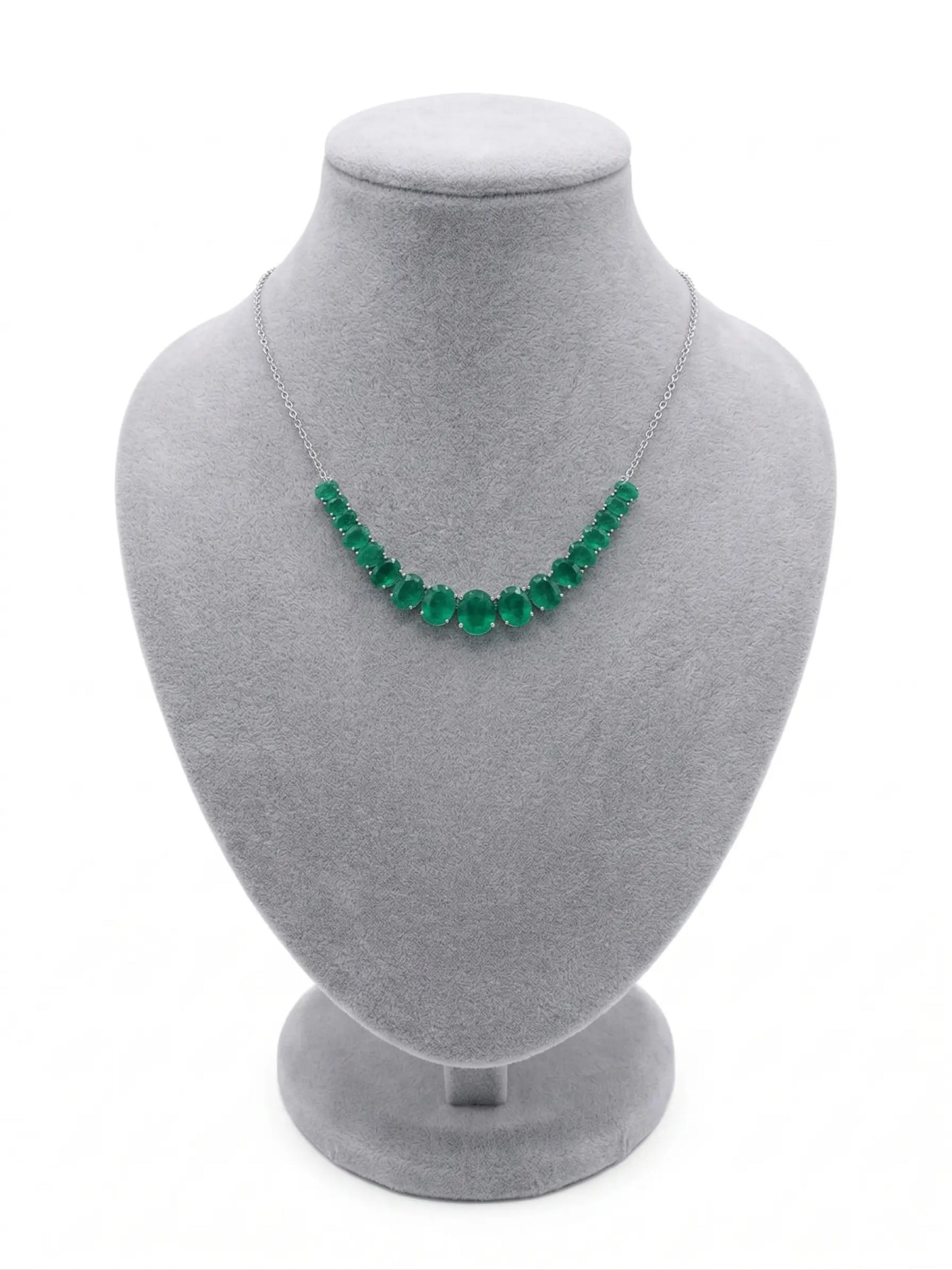 Green beaded necklace on a gray mannequin bust against a white background