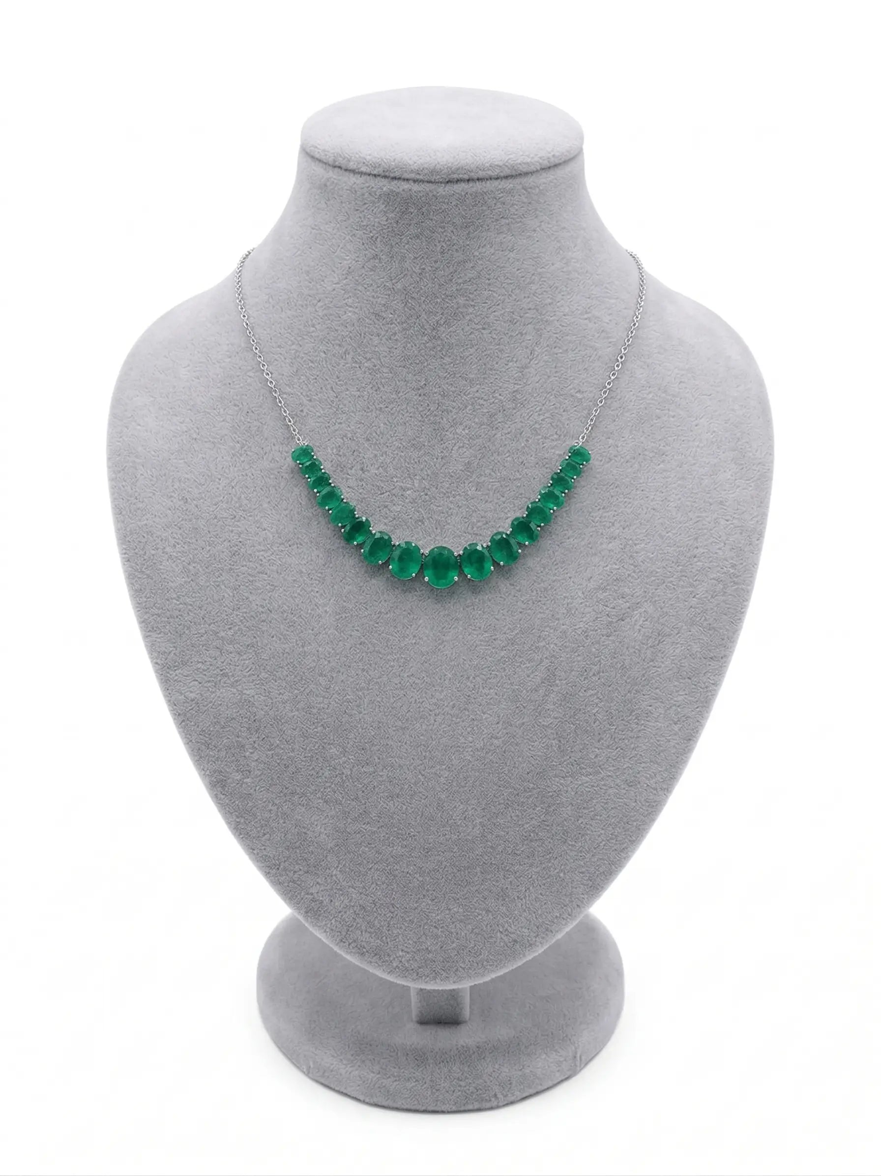 Green beaded necklace on a gray mannequin bust against a white background