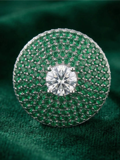 Green gemstone ring with a diamond center on a green fabric background