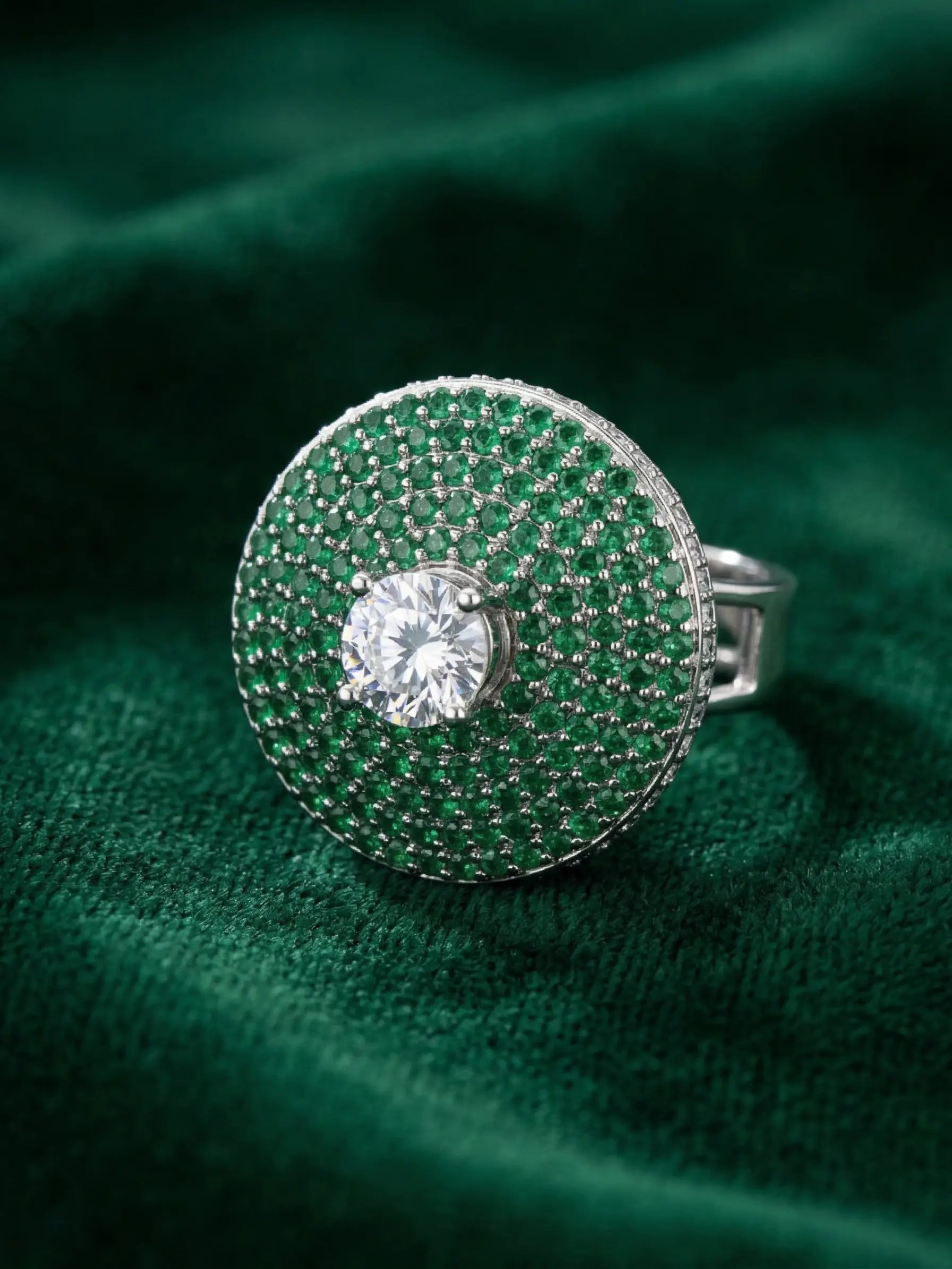 Silver ring with a central gemstone on a green textured fabric background