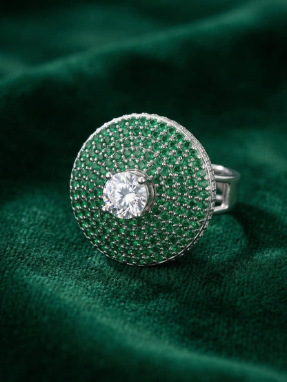 Silver ring with a central gemstone on a green textured fabric background