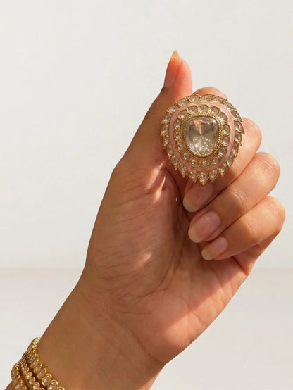 Hand holding a decorative ring with a clear gemstone against a neutral background