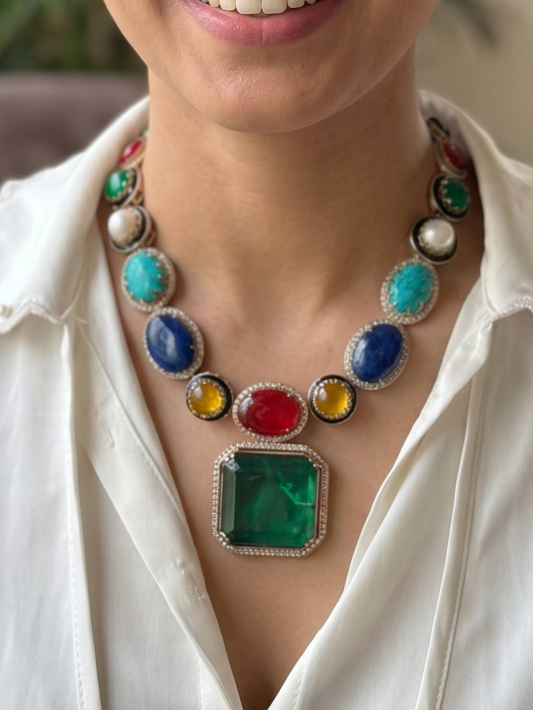 Colorful gemstone necklace worn by a person with a white shirt.