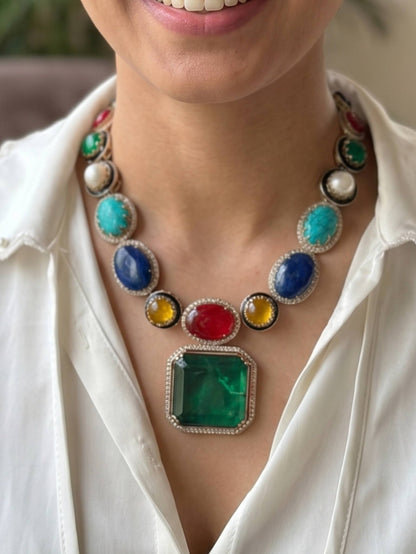 Colorful gemstone necklace worn by a person with a white shirt.