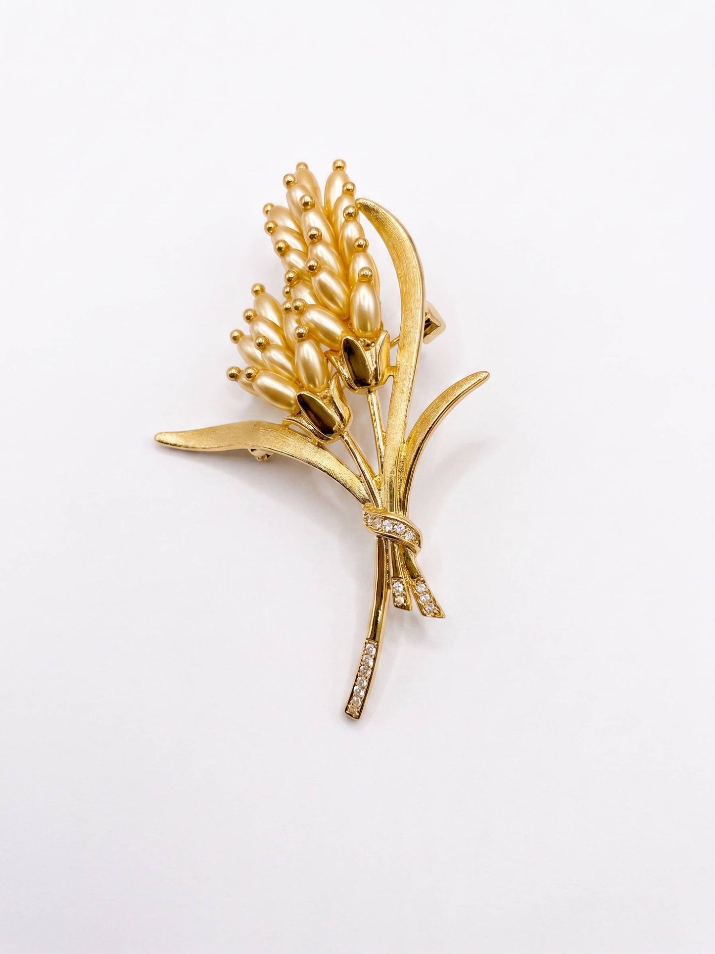 Gold brooch with wheat design on a white background