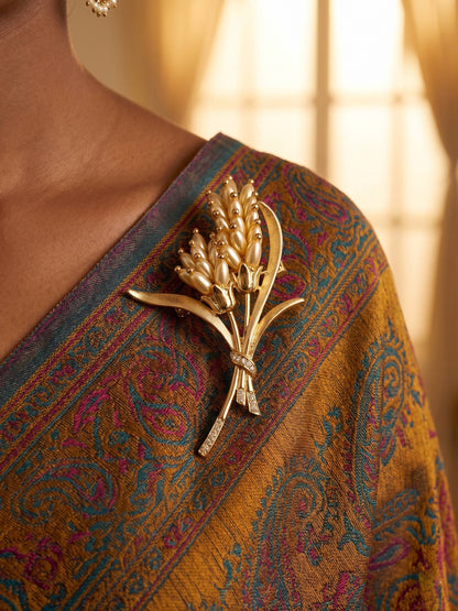 Gold brooch on a patterned fabric with a blurred background