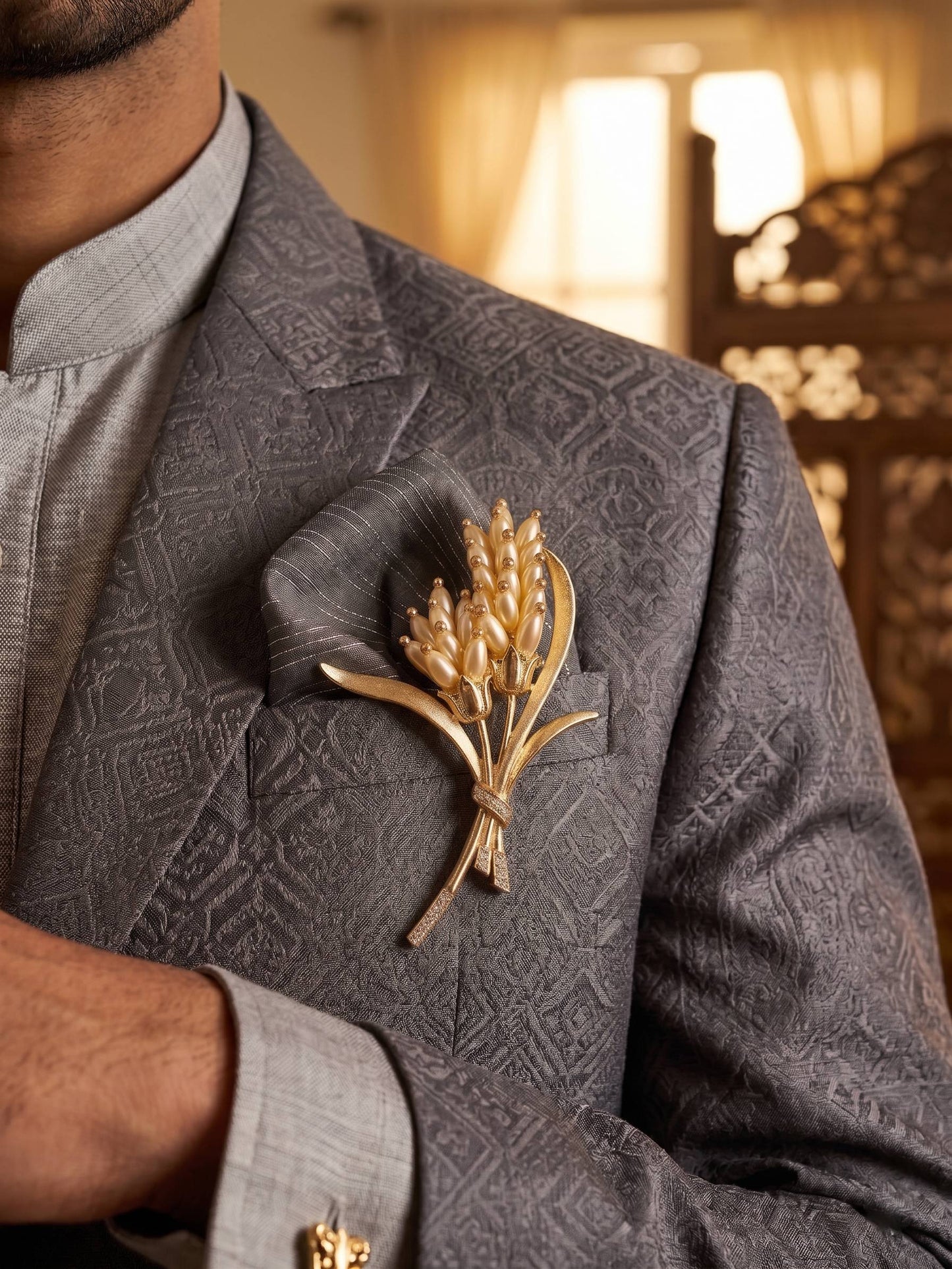 Gray patterned suit jacket with a gold brooch on a blurred background