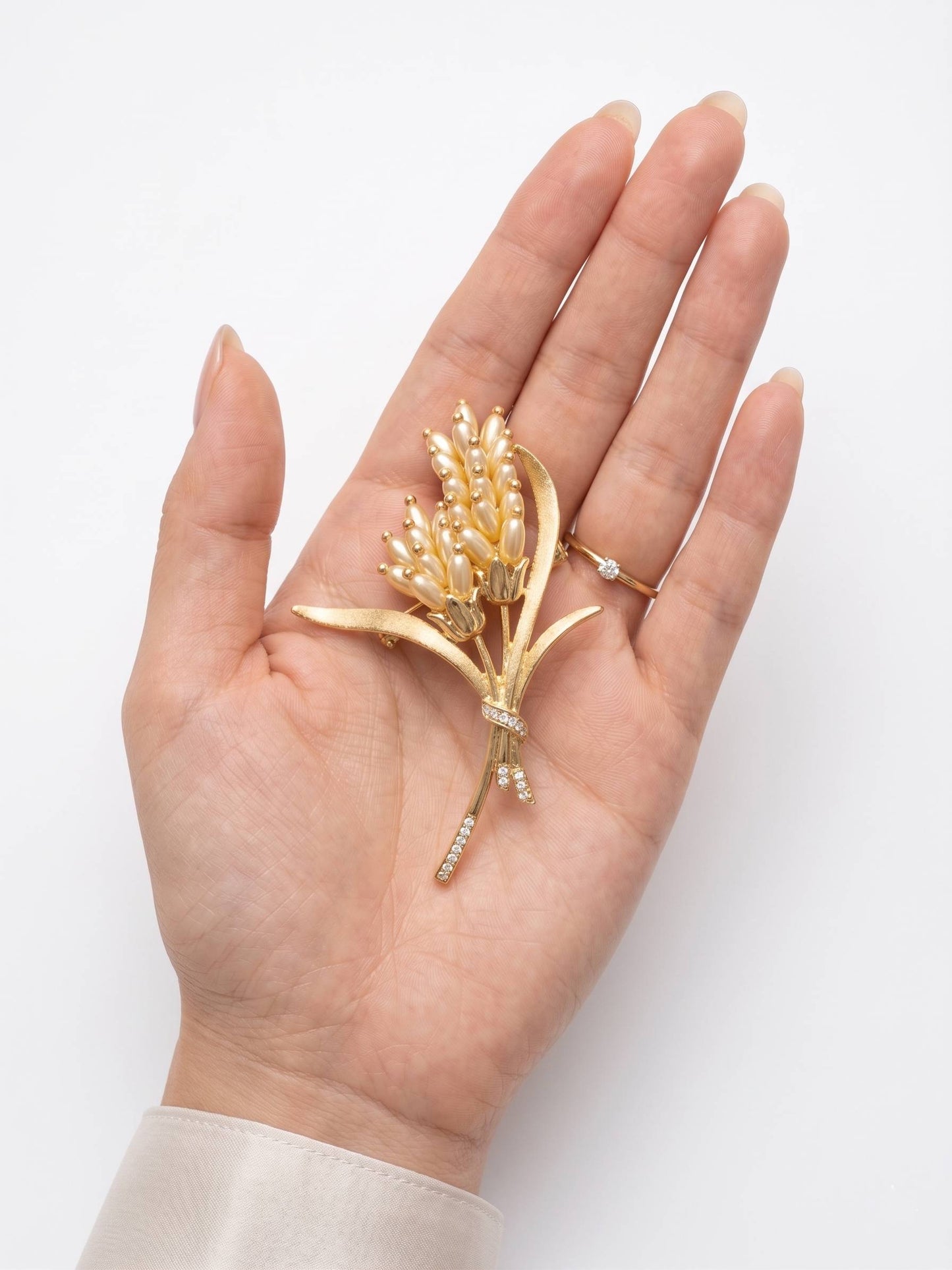 Gold brooch held in a hand against a white background